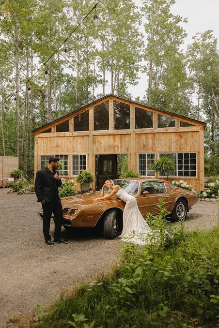 A couple beside a vintage car in front of the timber barn